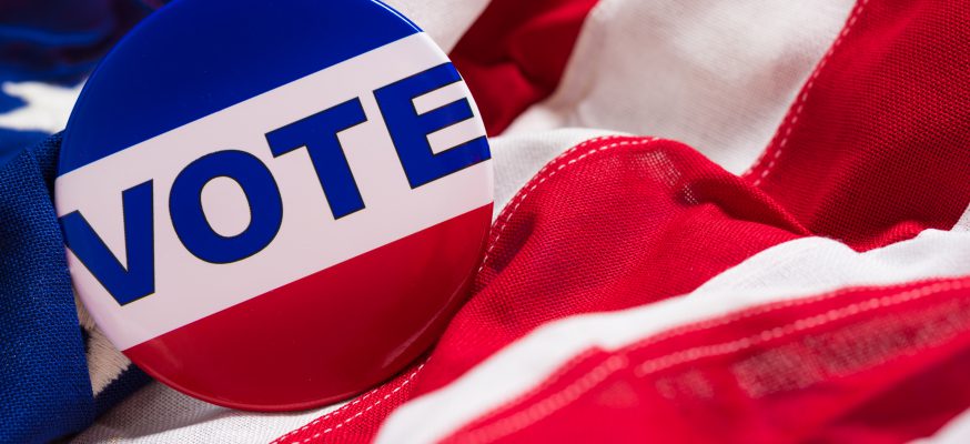 A "VOTE" pin or button on a flag of the United States