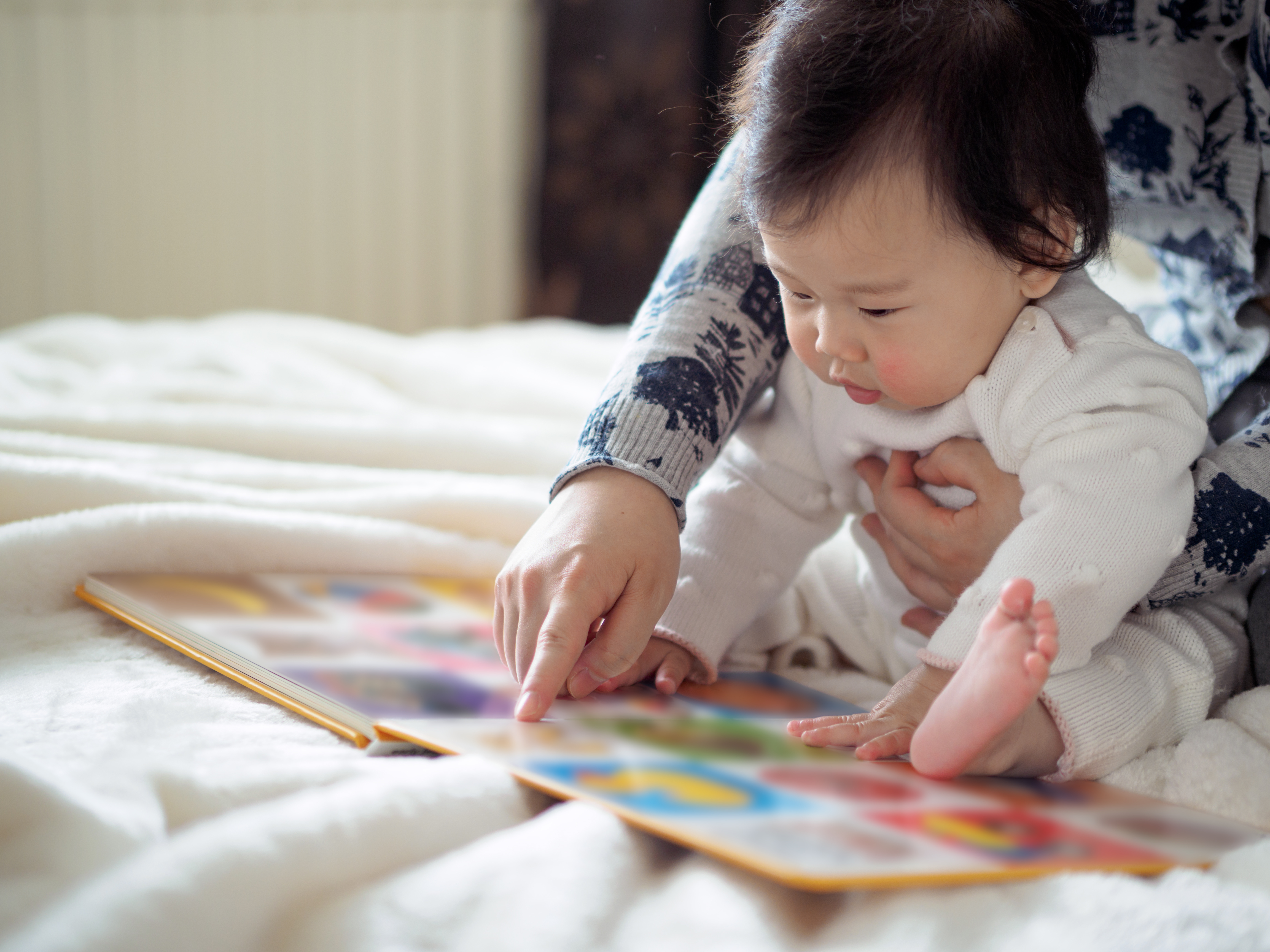 Baby and adult reading a book together