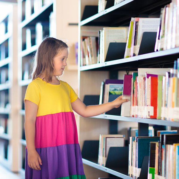 Girl getting a book from the library shelf